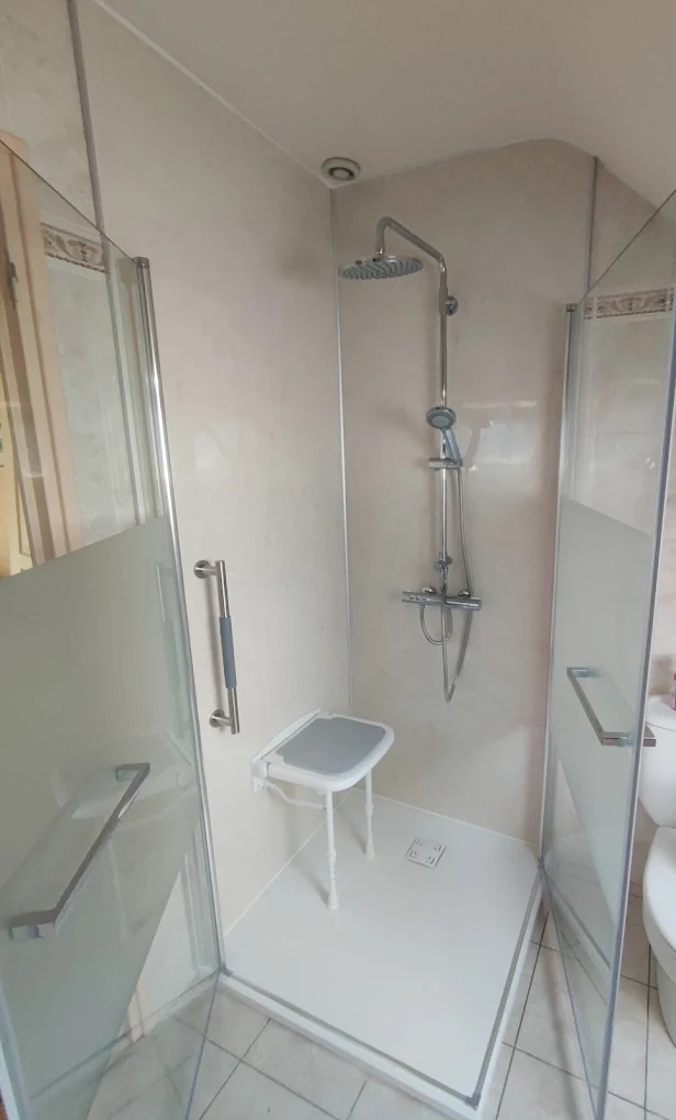 Douche sécurisée installée par Rénocem Habitat — colonne thermostatique, siège rabattable et barre d'appui